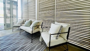 A room with two white sofas and chairs, a patterned rug, and a large window with blinds. - The Nola, 3BR Luxe Stay by Velvet Ditch Villas (Oxford)
