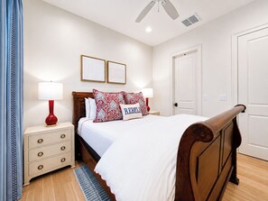 A bedroom with a wooden bed, two bedside tables, a nightstand, a red lamp, a white door, and a ceiling fan. - The Nola, 3BR Luxe Stay by Velvet Ditch Villas (Oxford)