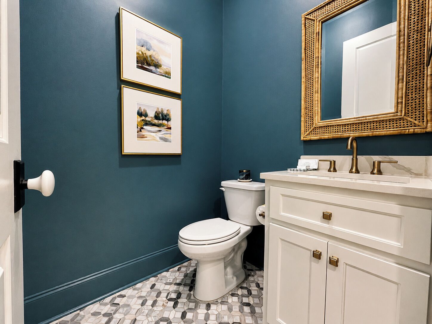 A bathroom with a white toilet, a white sink with gold fixtures, and a mirror with a golden frame.