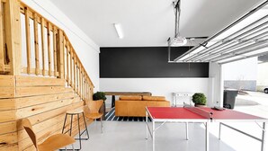 A modern interior with a wooden staircase, a ping pong table, and a blackboard wall. - The Nola, 3BR Luxe Stay by Velvet Ditch Villas (Oxford)