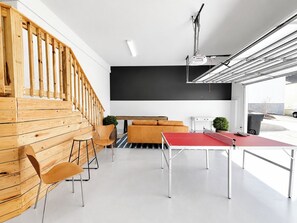 A modern interior with a wooden staircase, a ping pong table, and a blackboard wall. - The Nola, 3BR Luxe Stay by Velvet Ditch Villas (Oxford)