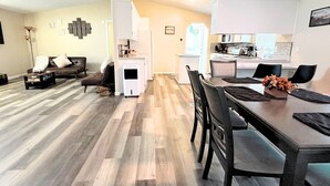 Un salon moderne avec un plancher en bois, un canapé, une table basse et un coin repas comprenant une table et des chaises.