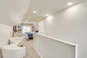 A narrow hallway with a staircase leading to a bedroom. The room has a bed with a blue blanket and pillows, a white dresser, and a chair. - 'The Maple Tree' Home: 14 Mi to Downtown Cleveland (Maple Heights)
