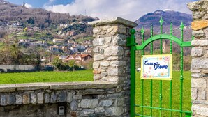A stone wall with a green metal gate and a sign that reads "Casa Giove".