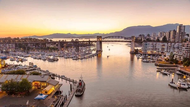 Una marina con barche, un ponte e edifici sullo sfondo.