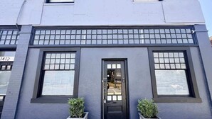 Un edificio con una porta nera, due finestre e due fioriere.