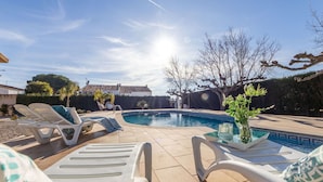 A swimming pool with lounge chairs and a potted plant.
