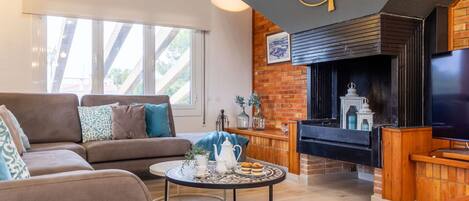 A cozy living room with a fireplace, a sofa, a coffee table, and a TV.