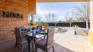 An outdoor patio with a brick wall, a pool, and lounge chairs.