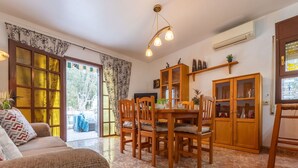 Un comedor con una mesa y sillas de madera, un sofá y un aparador con puertas de cristal.