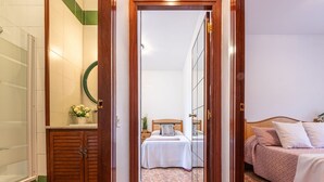 Habitación de hotel con un armario de madera, una cama con cabecera, una mesita de noche y un espejo en la pared.