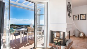A spacious balcony with a clear view of the sea, a dining area with outdoor furniture, and a fireplace with decorative items. - Stunning private villa for 8 people with A/C, private pool, WIFI, TV and terrace (Frigiliana)