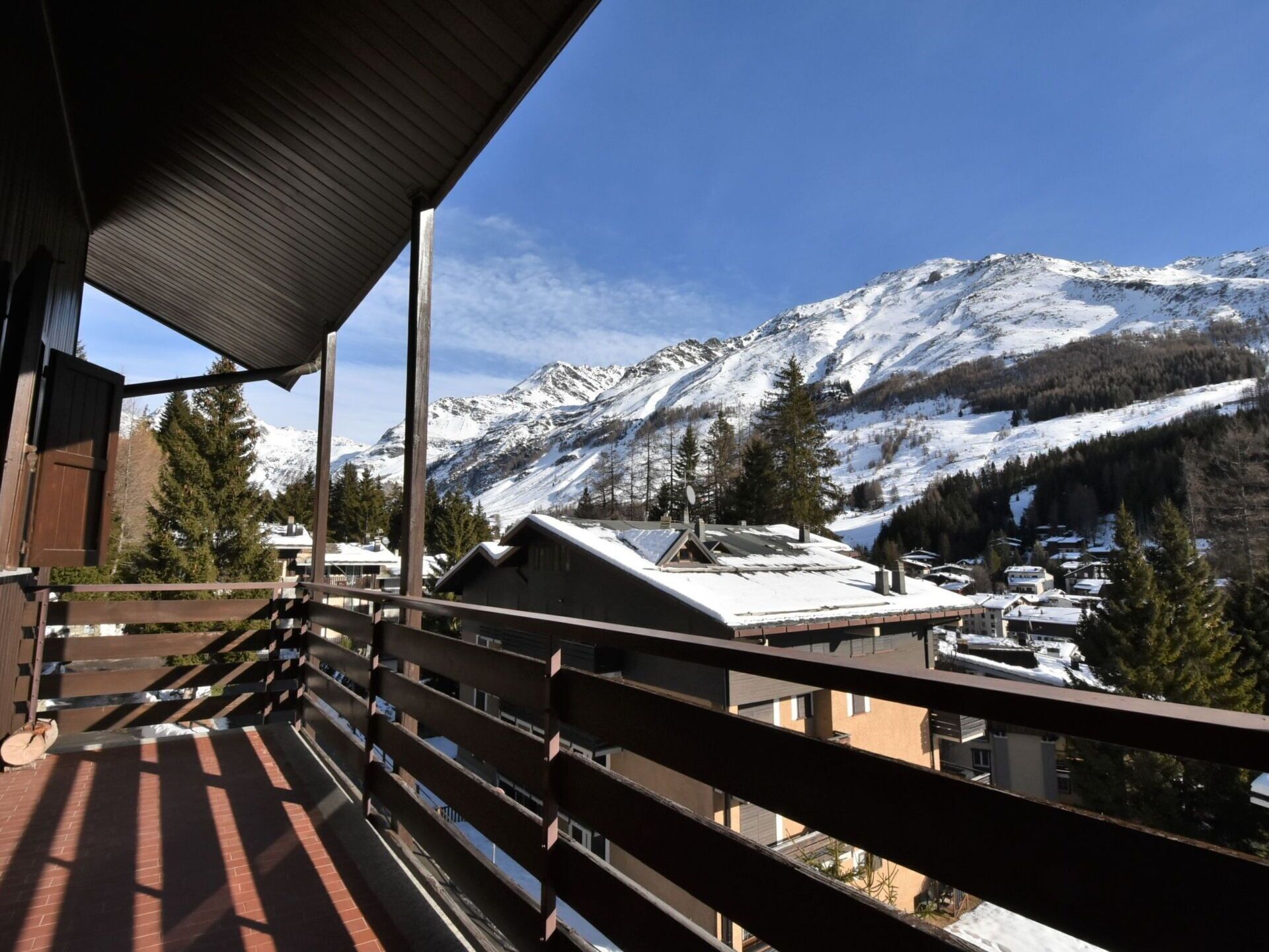 Un balcon offrant une vue sur des montagnes enneigées et un petit village.