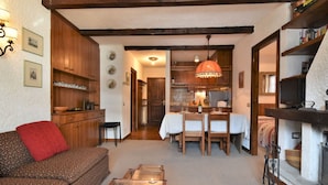 A cozy living room with a sofa, a glass coffee table, and a dining area with a table and chairs. - Lovely apartment for 5 people with WIFI, TV and terrace (Madesimo)