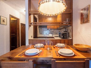 A wooden dining table set with plates, glasses, and cutlery, with a kitchen in the background. - Beautiful apartment for 5 people with WIFI, TV and terrace (Madesimo)