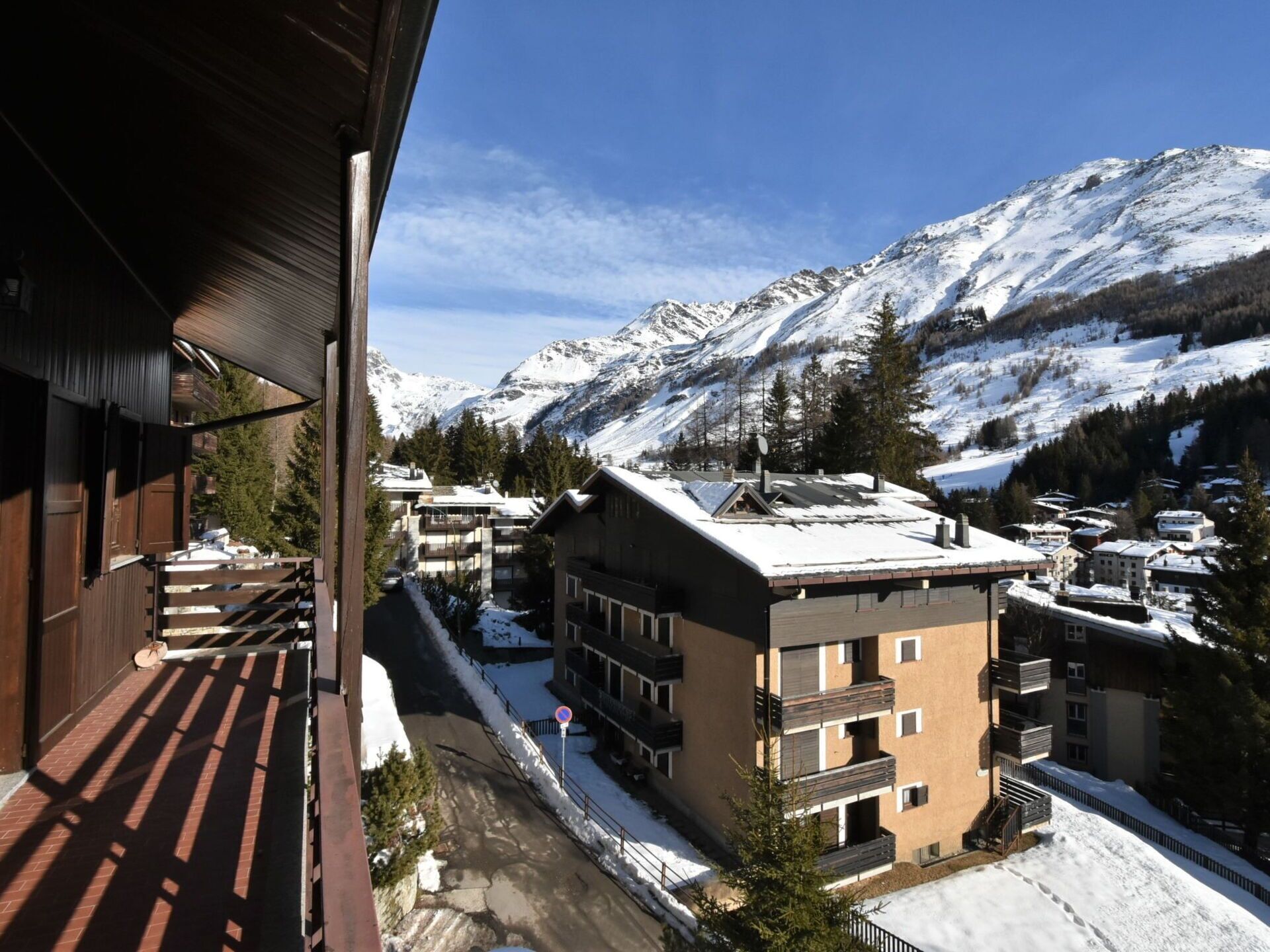 A mountain resort with snow-covered buildings and a clear view of snow-capped mountains.