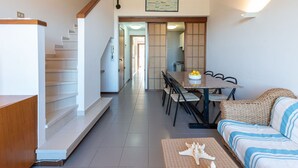 Un intérieur moderne comprenant un escalier, un coin repas et un espace détente avec un canapé en osier.