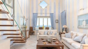 A spacious living room with a staircase, a large window with a view, and a dining area.