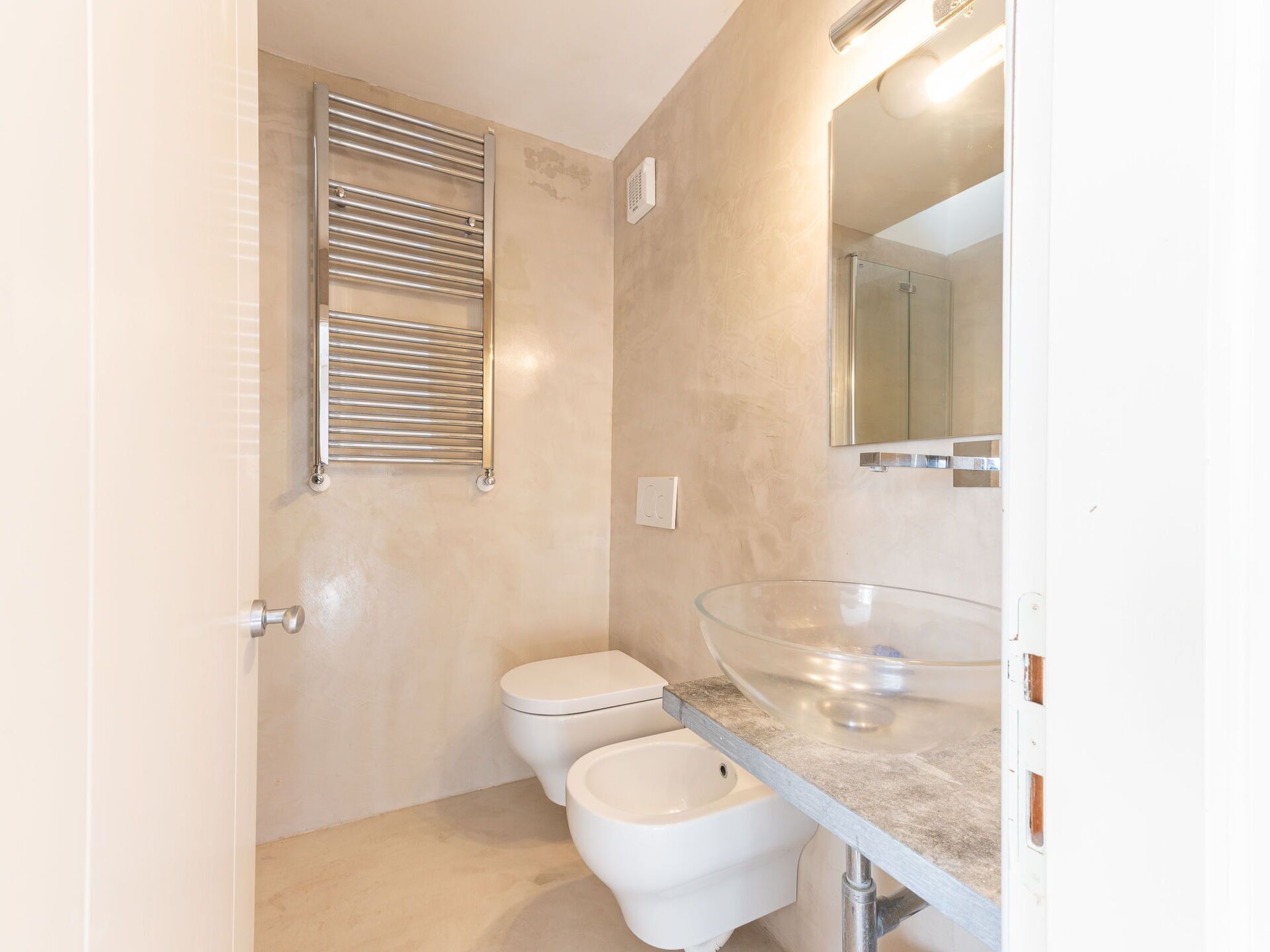 Un baño pequeño con inodoro, bidé y lavabo de cristal.