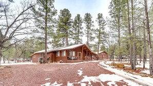 A cabin with a large deck and a covered porch, surrounded by tall pine trees. - 2 Fire Pits & Covered Deck: Cabin in Happy Jack! (Happy Jack)
