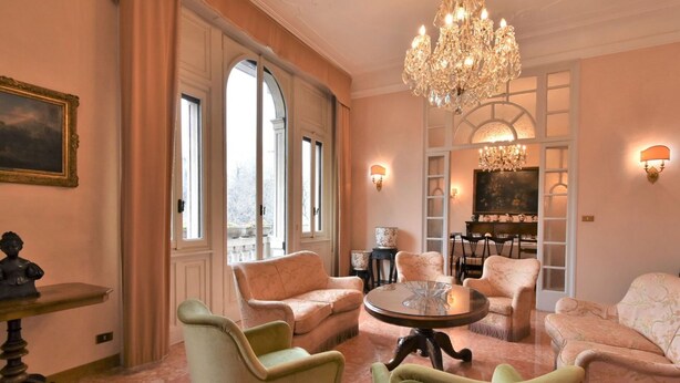 Une pièce spacieuse, agrémentée d’un lustre, de sièges confortables et de grandes fenêtres.