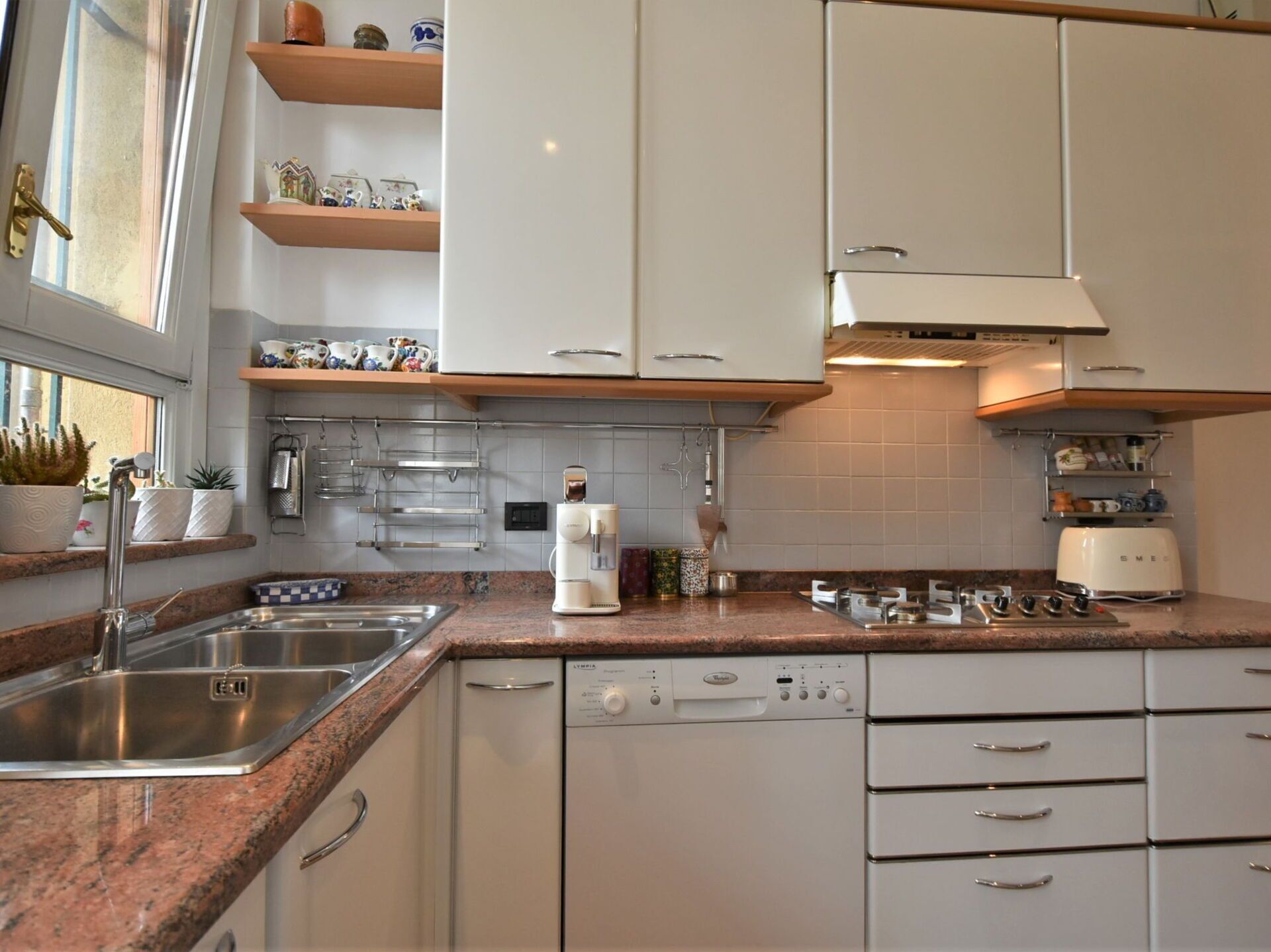 Eine moderne Küche mit weißen Schränken, Granit-Arbeitsplatten, einer Kaffeemaschine und einem Geschirrspüler.