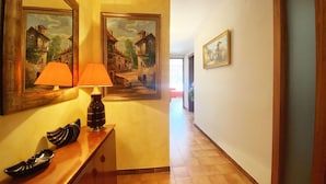 A hallway with wooden flooring, a wooden bench with a lamp, and two framed paintings on the walls. - Beautiful apartment for 6 guests with A/C, WIFI, TV and terrace (Castell-platja D'aro)