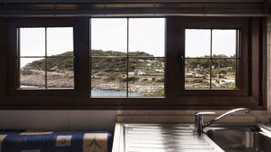 A kitchen with a large window overlooking a coastal landscape. - Lovely apartment in villa for 4 guests with A/C, TV, terrace and pets allowed (Mali Lošinj)