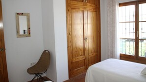 Ein Schlafzimmer mit Holzschrank, Stuhl, Bett und Fenster mit Blick.