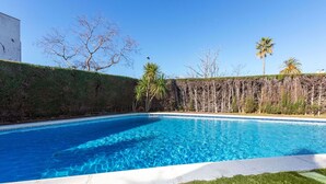 A swimming pool with clear blue water, surrounded by a grassy area and a hedge. - Cosy apartment for 6 people with WIFI, pool, TV and terrace (Castell-platja D'aro)