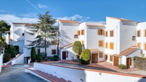 A row of white buildings with red-tiled roofs, a paved walkway, and green landscaping. - Cosy apartment for 6 people with WIFI, pool, TV and terrace (Castell-platja D'aro)