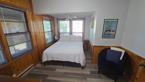 Ein Schlafzimmer mit einem Bett, Holzwänden, einem Deckenventilator und einem Poster an der Wand.