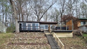Ein modernes Haus mit einer Steinschmalseite und einer Holztreppe, die zu einer Terrasse führt.