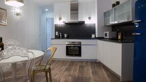 Eine moderne Küche mit weißen Schränken, Edelstahlgeräten und einem blauen Kühlschrank.