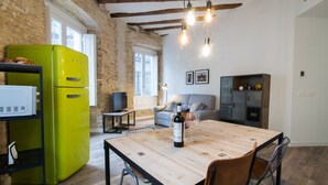 Une cuisine avec une table en bois, un réfrigérateur vert et un canapé gris.