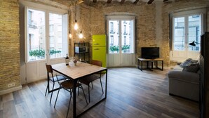 Un espace de vie compact comprenant un coin repas, un canapé, un téléviseur et une cuisine équipée d’un réfrigérateur vert.