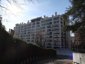 Stunning multi-story building with spacious balconies and large windows, surrounded by lush greenery.