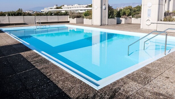 A rectangular swimming pool with clear blue water, surrounded by a tiled deck. - Lovely apartment for 6 people with WIFI, pool, TV, balcony and panoramic view (Le Petit-saconnex)
