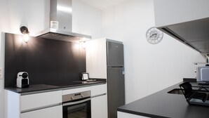 A modern kitchen with a built-in oven, a stainless steel refrigerator, and a black countertop. - PPRINCIPAL B - P B - APARTAMENTOS ALMADA - Plaza del Pilar (Zaragoza)