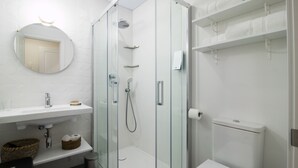 A modern bathroom with a glass-enclosed shower, a white sink with a mirror, and a toilet. - PRIMERO B - 1 B - APARTAMENTOS ALMADA - Plaza del Pilar (Zaragoza)