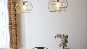 A round dining table with six chairs, two pendant lights, and a potted orchid. - PRIMERO B - 1 B - APARTAMENTOS ALMADA - Plaza del Pilar (Zaragoza)