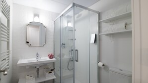 A modern bathroom with a glass-enclosed shower, a white sink, and a toilet.