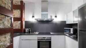 A modern kitchen with white cabinets, a stainless steel range hood, a built-in oven, a microwave, and a coffee maker. - PPRINCIPAL D - PD - APARTAMENTOS ALMADA - Plaza del Pilar (Zaragoza)