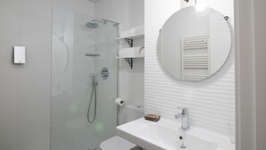 A modern bathroom with a glass-enclosed shower, a round mirror, and a white sink. - PPRINCIPAL D - PD - APARTAMENTOS ALMADA - Plaza del Pilar (Zaragoza)
