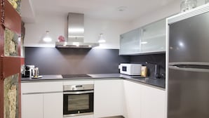 A modern kitchen with white cabinets, stainless steel appliances, and a wooden floor. - SEGUNDO D - 2D - APARTAMENTOS ALMADA - Plaza del Pilar (Zaragoza)