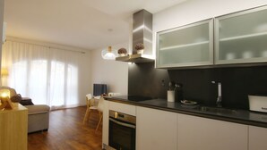 A modern kitchen with white cabinetry, a stainless steel range hood, and a black countertop. - ENTRESUELO A - E A - Apartamentos Almada - Plaza del Pilar (Zaragoza)