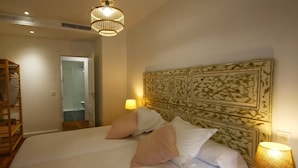 A hotel room with a large bed, a headboard with a decorative panel, a bedside lamp, and a wooden wardrobe. - ENTRESUELO A - E A - Apartamentos Almada - Plaza del Pilar (Zaragoza)
