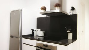 Una cocina compacta con un refrigerador, una tostadora y un microondas sobre la encimera.