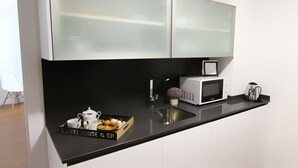 Una cocina moderna con encimera negra, microondas blanco, pileta y espacio para café.