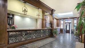 A reception area with a wooden reception desk, ornate metal railings, and hanging lantern-style lights.